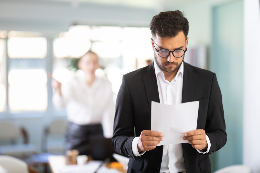 Mann im Büro hält ein Kündigungsschreiben in der Hand