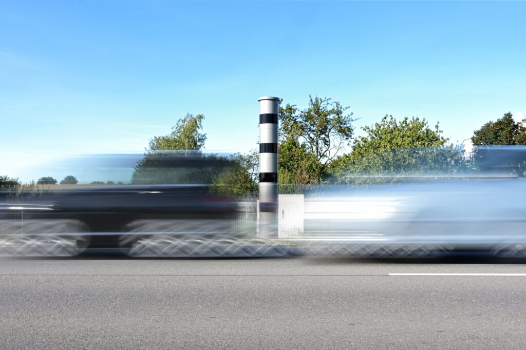 Fahrzeuge fahren an einer Geschwindigkeitsmessanlage vorbei